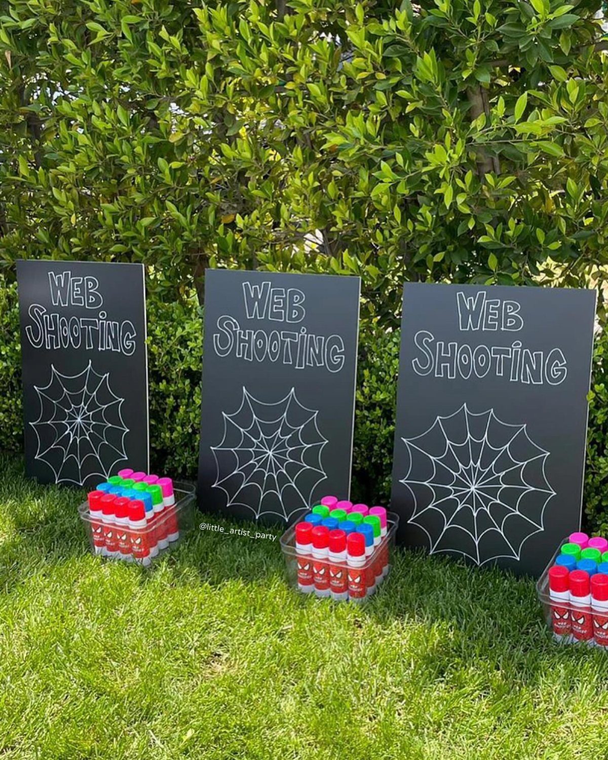Web shooting game setup with black boards and colorful canisters on green grass