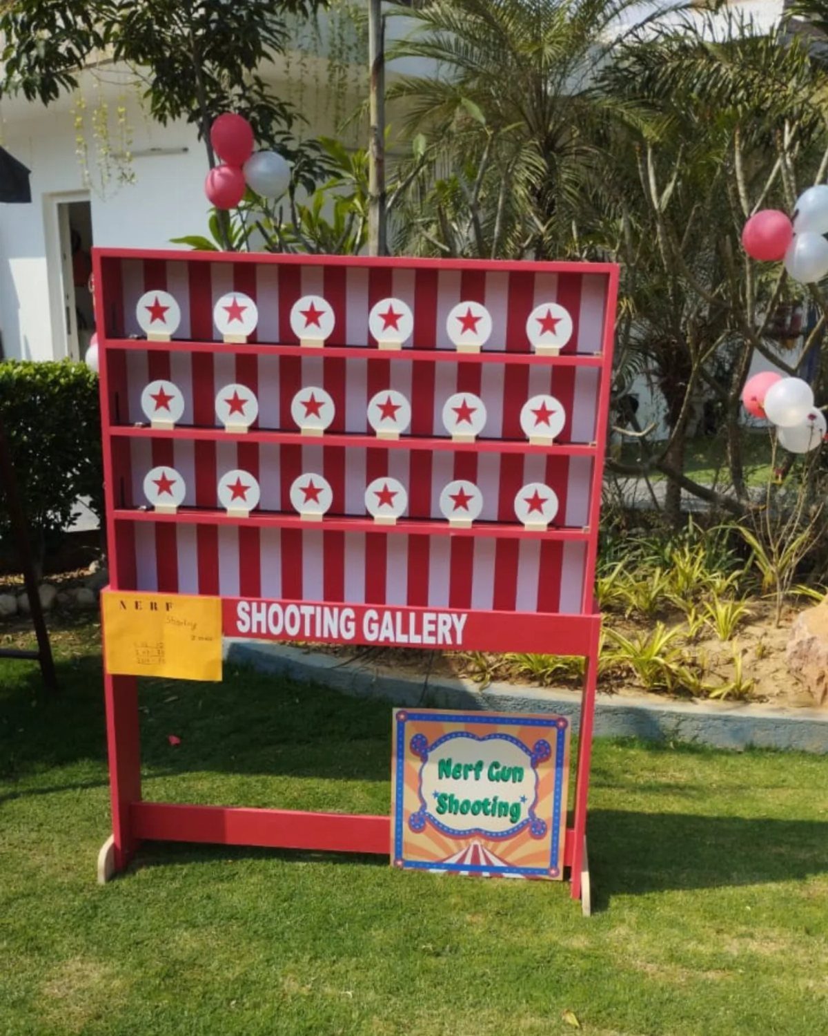 Red and white striped shooting gallery stand with targets on a green lawn.