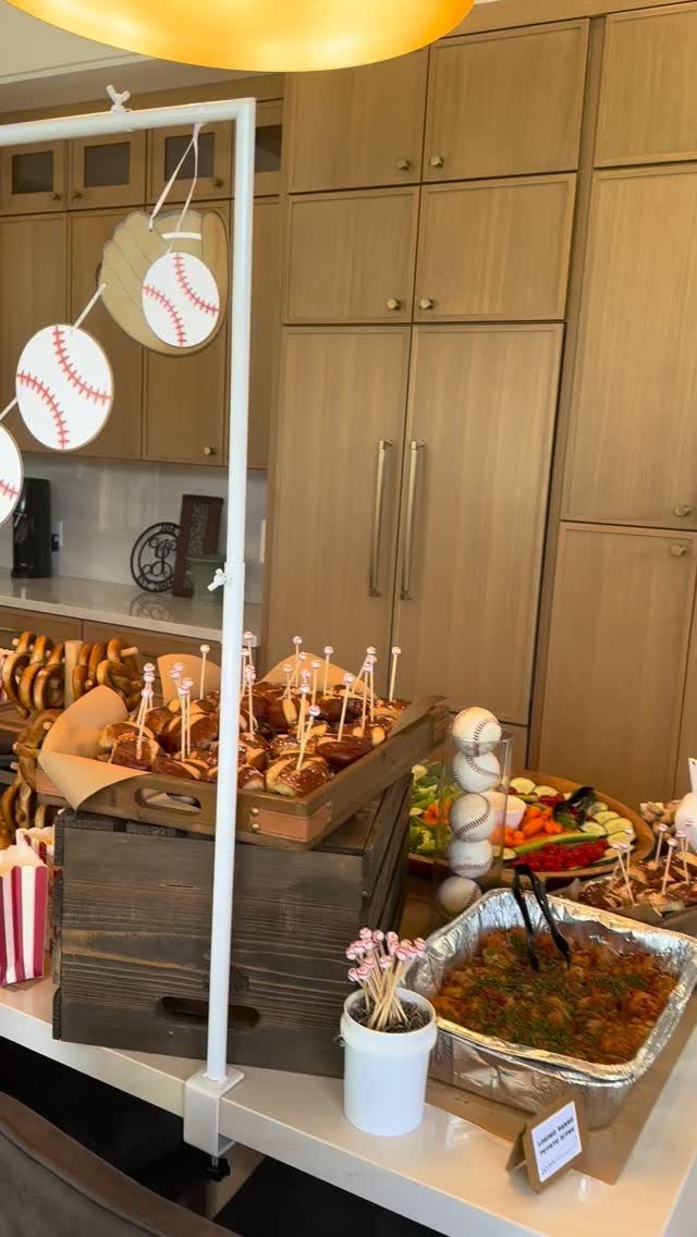 Food spread with sliders and vegetables decorated with baseball cutouts for a party.