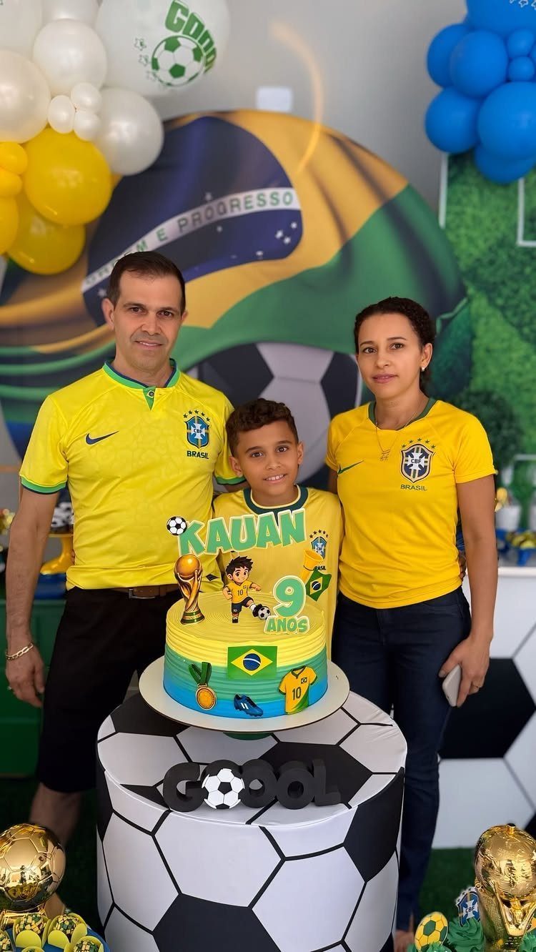 Family in Brazil soccer jerseys posing with a soccer themed birthday cake