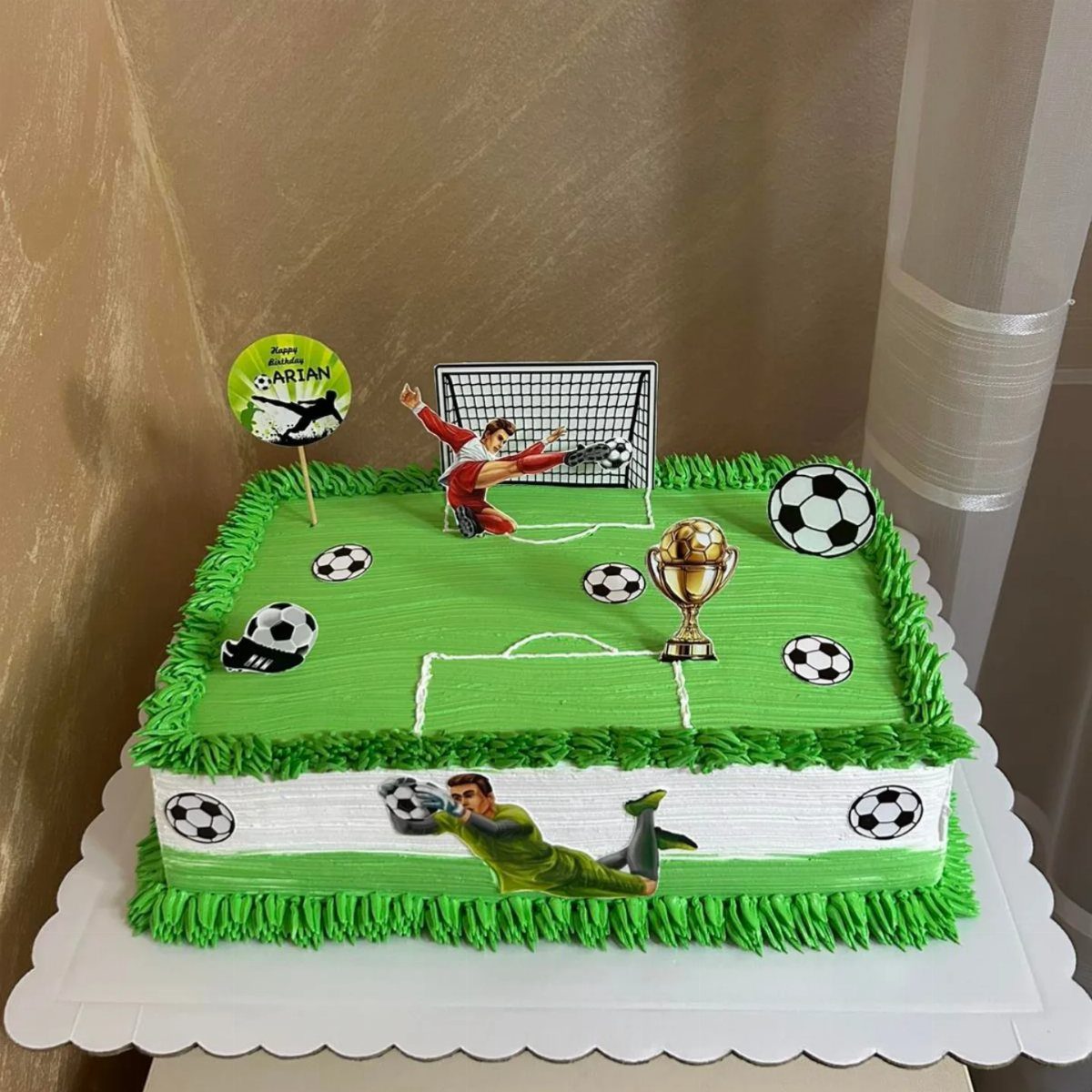 Soccer field cake with green frosting, a gold trophy, and player figures.