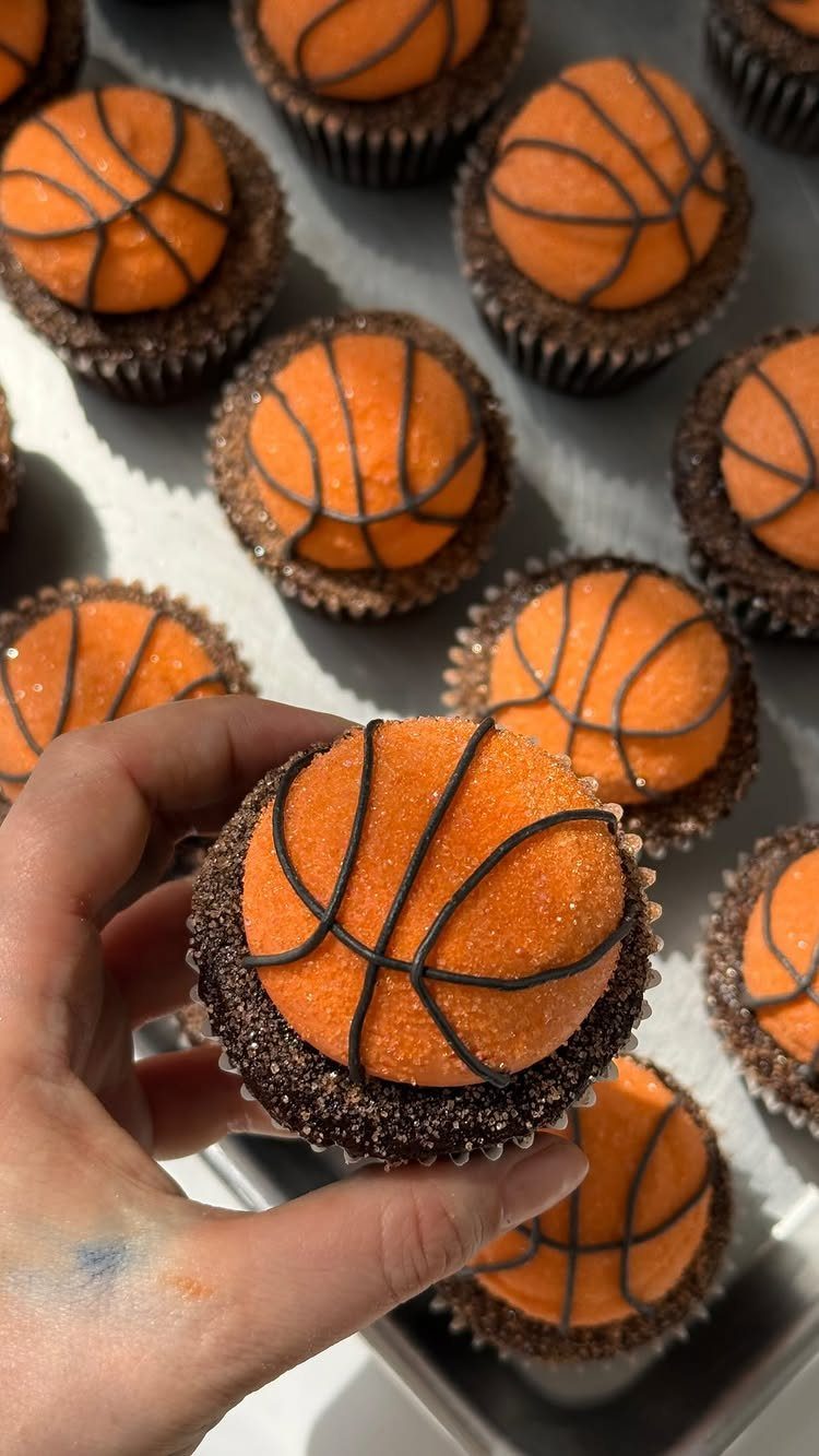 Basketball themed cupcakes with orange ball decorations on a metal baking tray