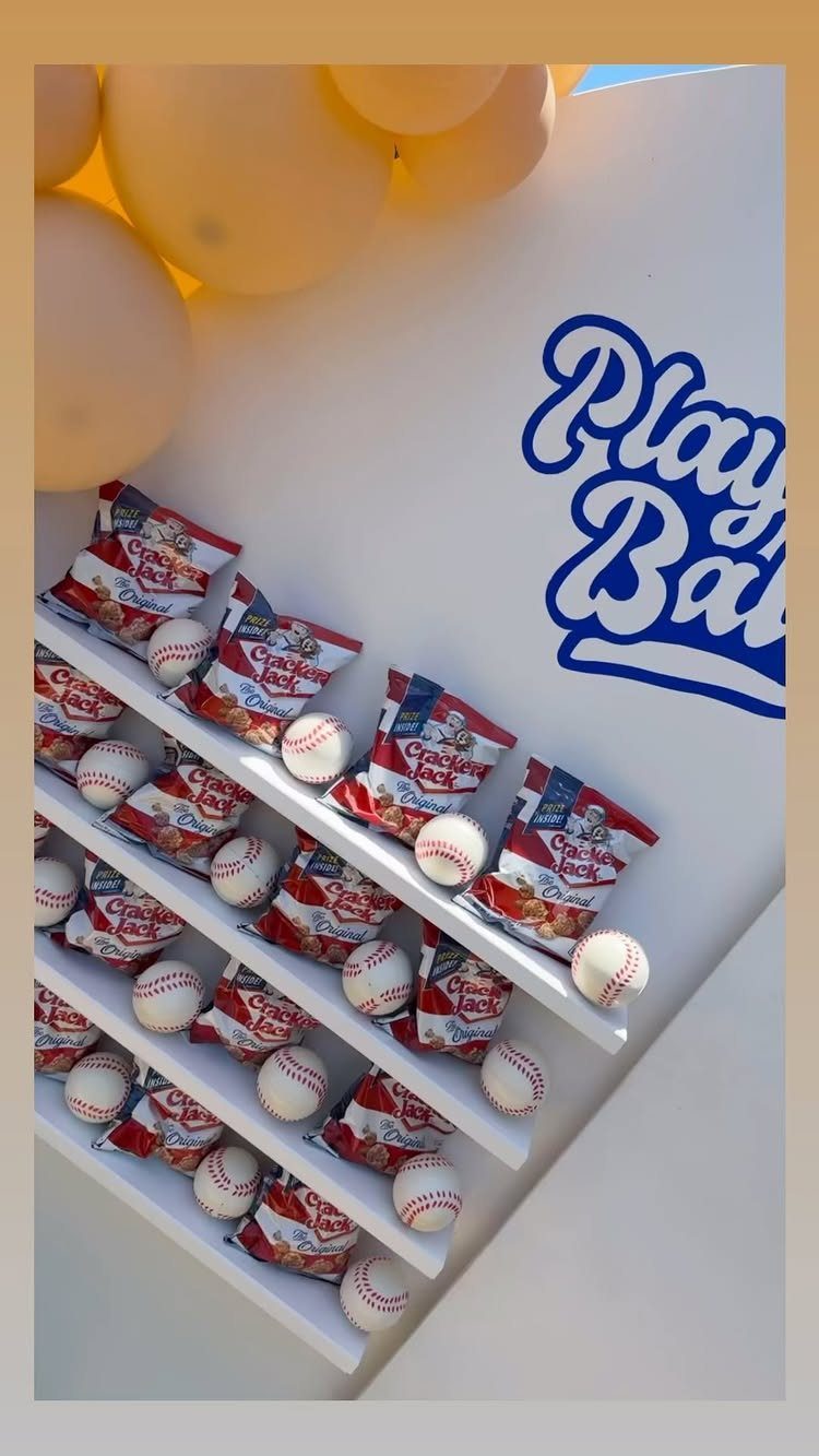 Baseball themed party display with Cracker Jack, baseballs, and yellow balloons.