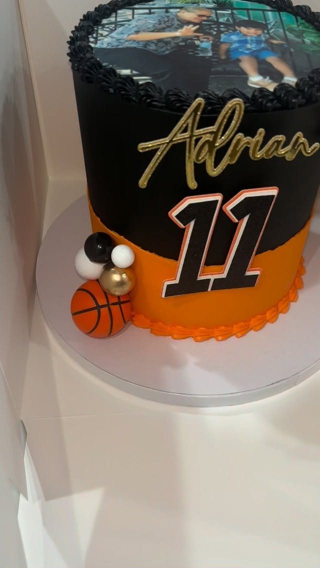 Sports themed birthday cake with orange and black frosting and a basketball decoration