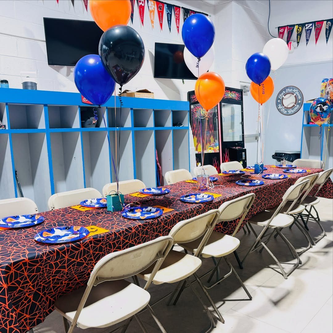 Party table with spiderweb tablecloth and balloons in a sports facility room