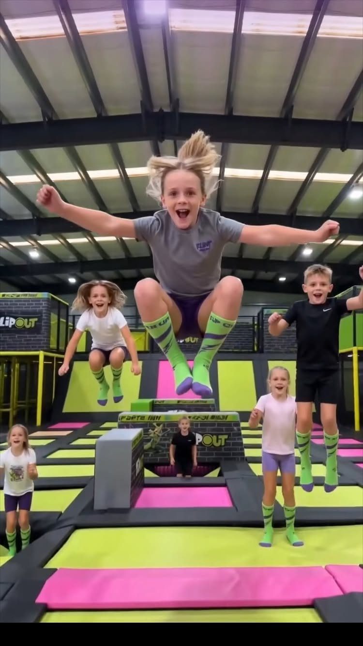 Children jumping on trampolines in a colorful indoor sports and recreation center.