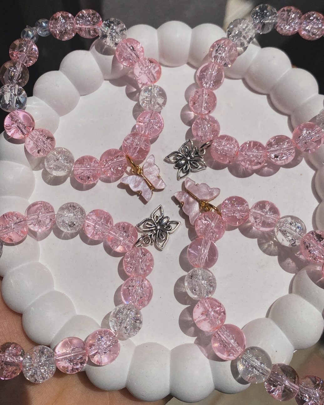 Pink and clear beaded bracelets with butterfly charms on a white tray