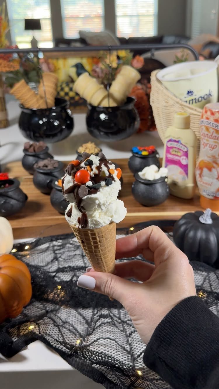 Ice cream cone with chocolate syrup and candies at a themed dessert station.