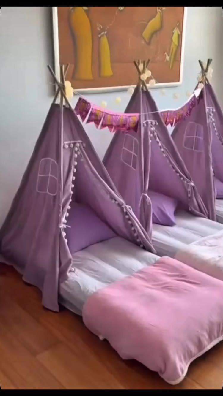 Three purple teepee tents with pink blankets and pillows for a sleepover party.