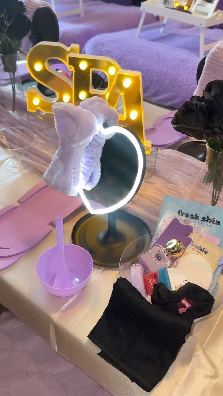 Spa setup with glowing SPA sign, ring mirror, and skincare products on a table.