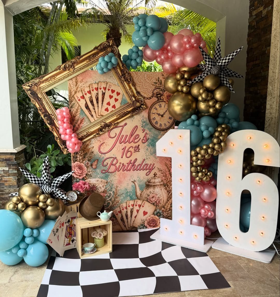 Alice in Wonderland themed birthday decor with large illuminated 16 and balloons.