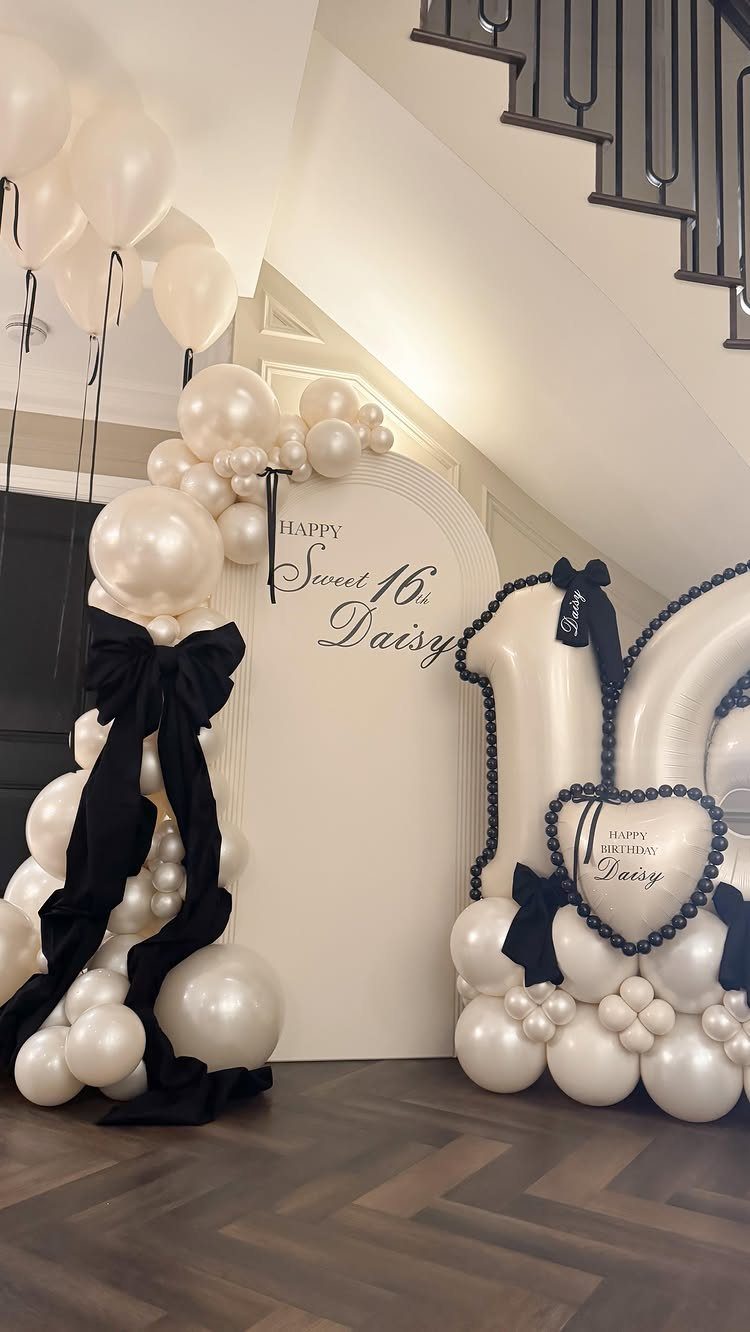 White and cream balloon arch and large 16 balloons for a Sweet 16 party.