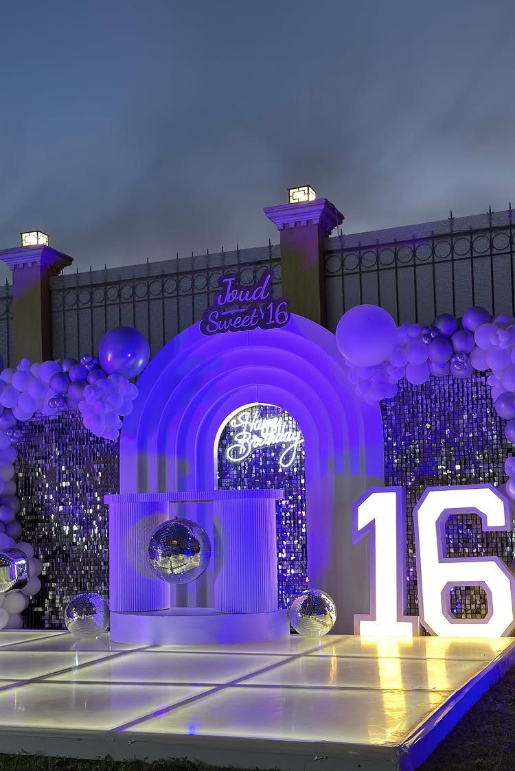 Illuminated dance floor with disco balls and a large glowing 16 sign.