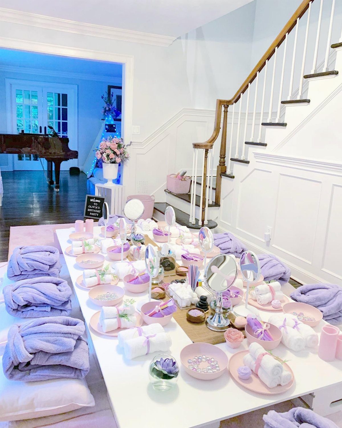 Spa party setup with purple towels and pampering supplies on a white table.