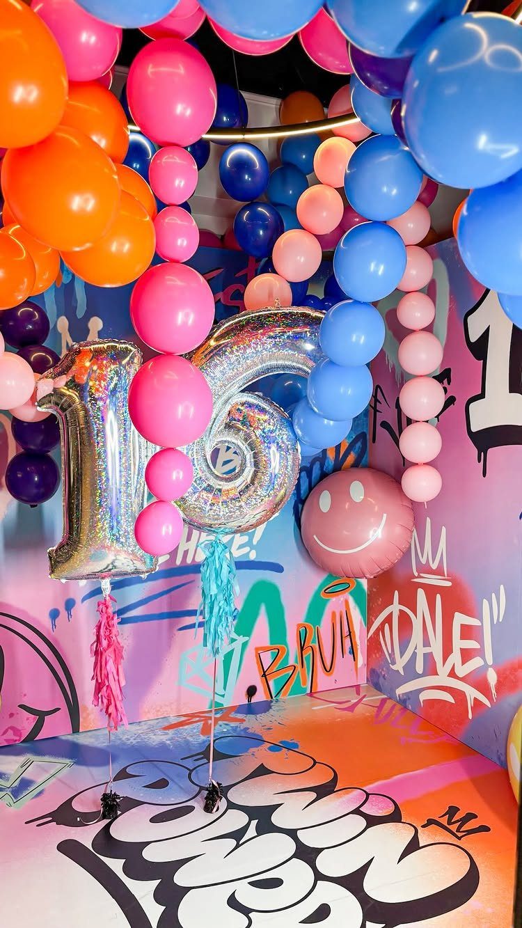 Silver 16 balloons and colorful balloon arches against a vibrant graffiti art background.