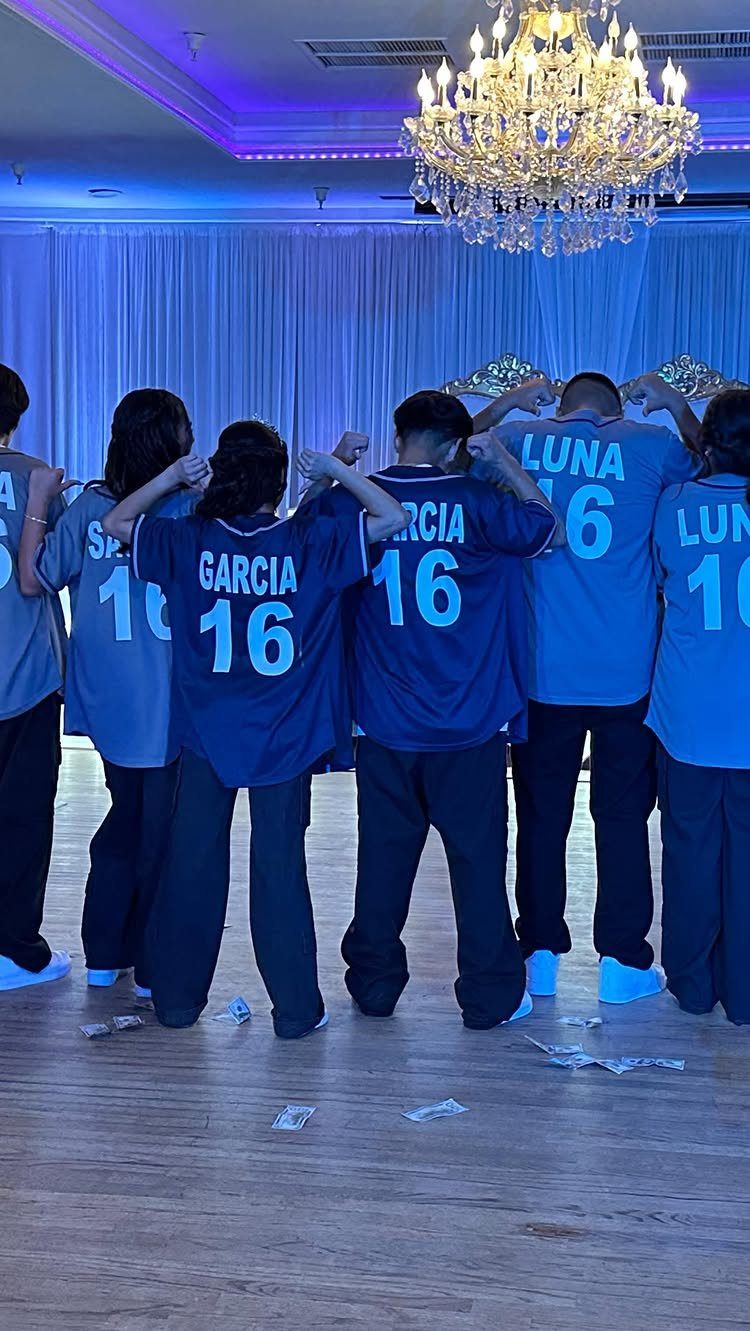 Group of people wearing matching blue jerseys with number 16 under a chandelier.