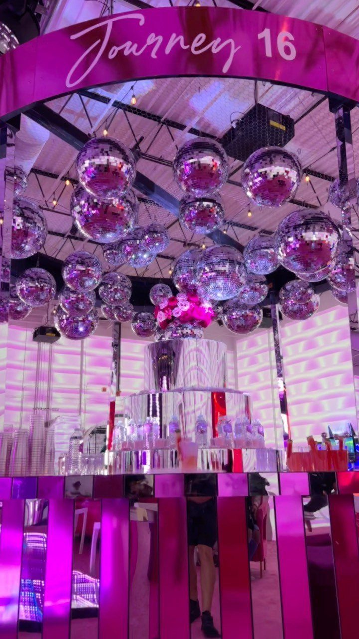 Pink party decor with silver disco balls and a Journey 16 banner.