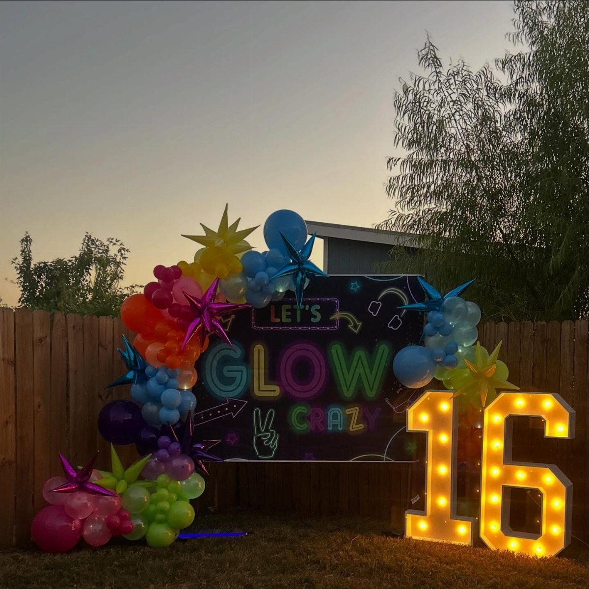 Neon birthday party setup with glow sign, colorful balloons, and illuminated 16 numbers.