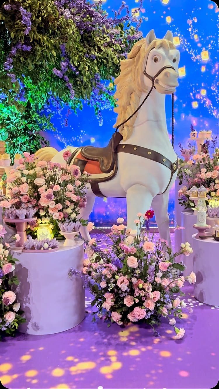 White horse statue with blonde mane surrounded by pink flowers and purple decor.