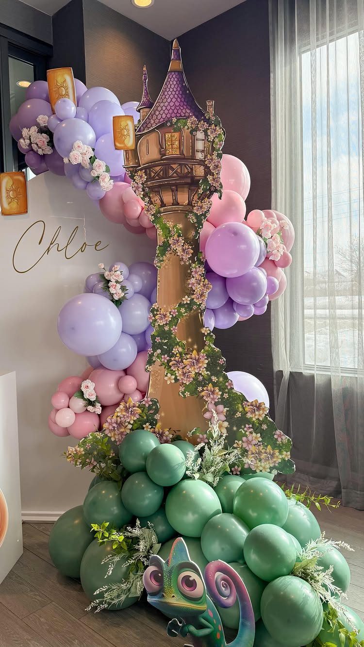 Tangled themed party backdrop with a tower, colorful balloons, and Pascal cutout.