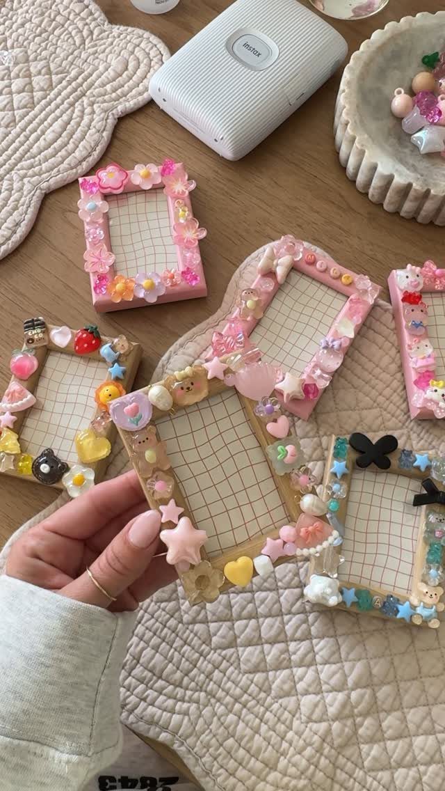 Handmade colorful decorative frames with charms and flowers on a wooden table.