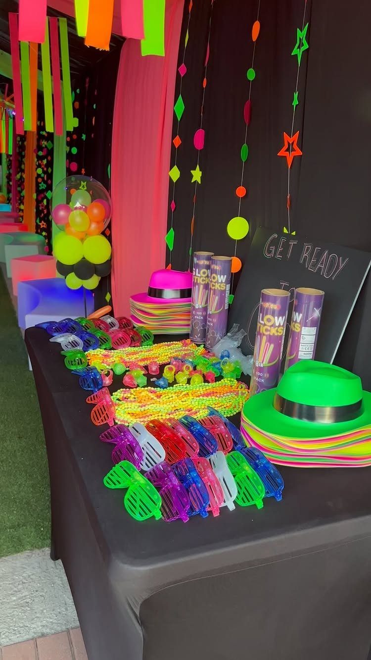 Neon glow party accessories including glasses and hats on a black table.