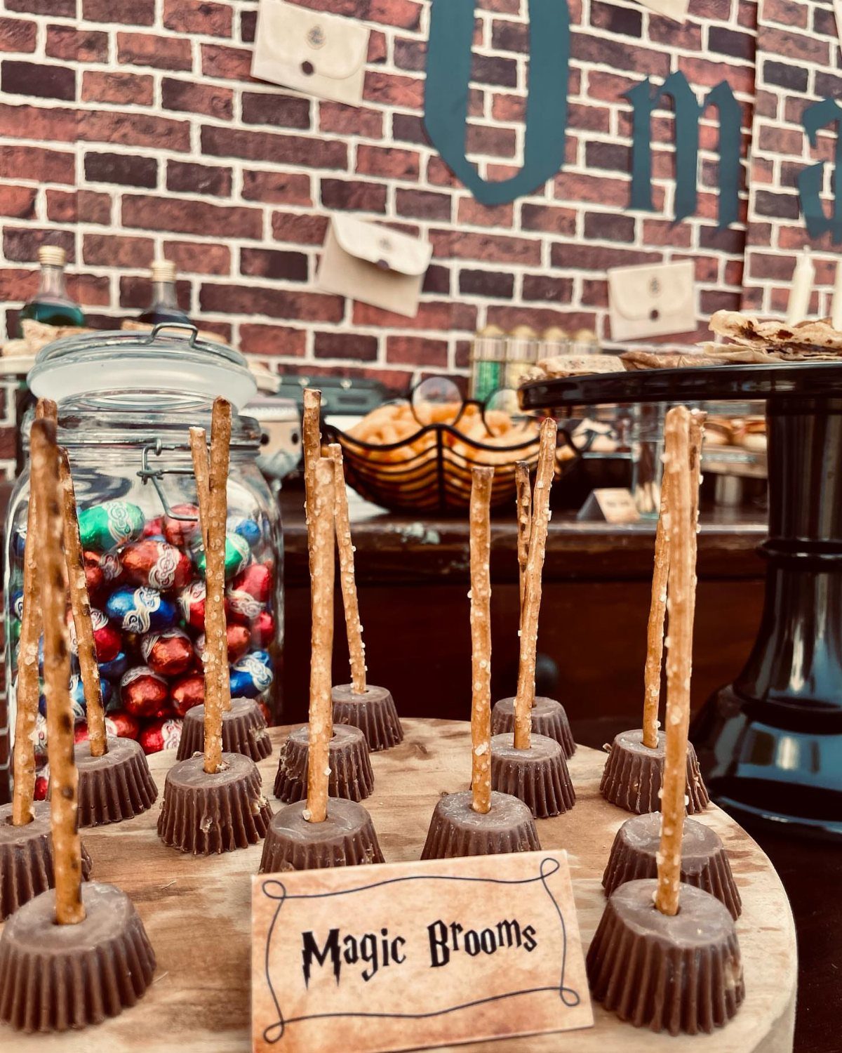 Pretzel stick treats shaped like magic brooms on a themed party table.
