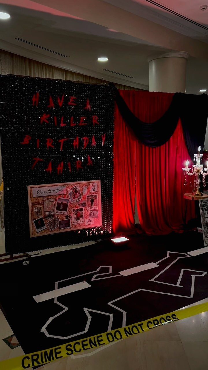 Crime scene party setup with red curtains, caution tape, and body outline.
