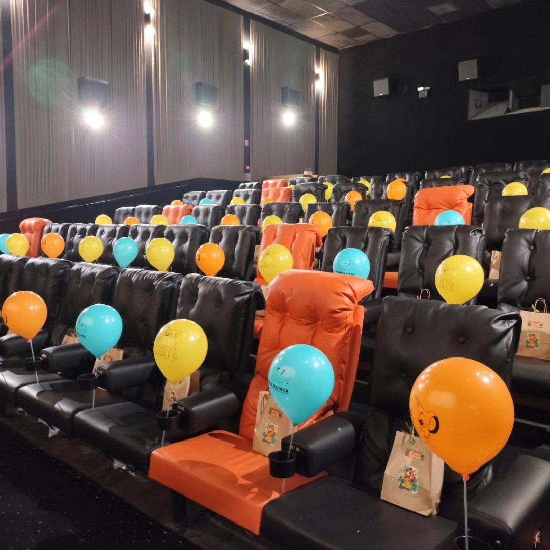 Cinema seats decorated with colorful balloons and gift bags for a private screening.