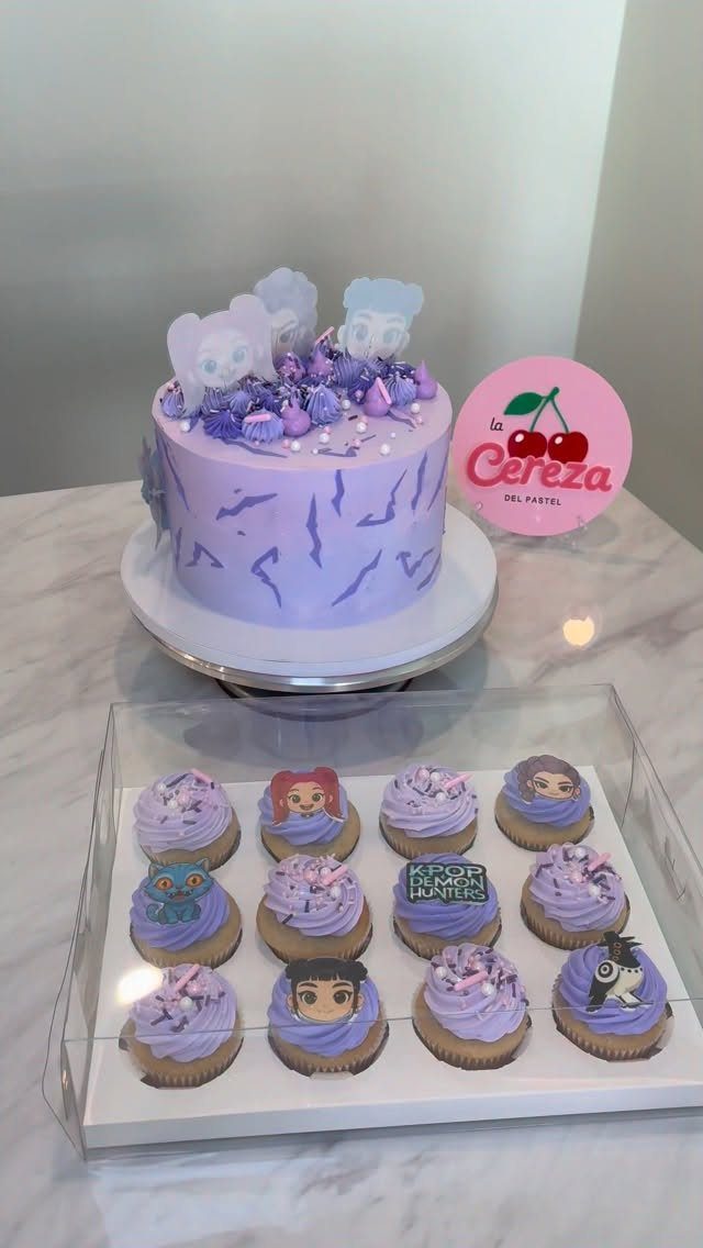 Purple themed cake and matching cupcakes with cartoon character toppers on white surface