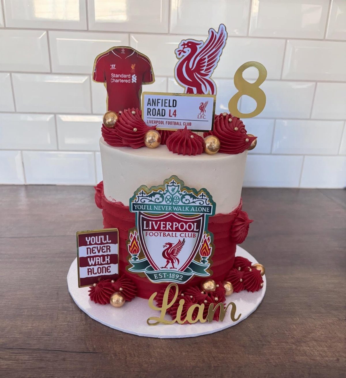 Liverpool Football Club themed birthday cake with red frosting and club logos.