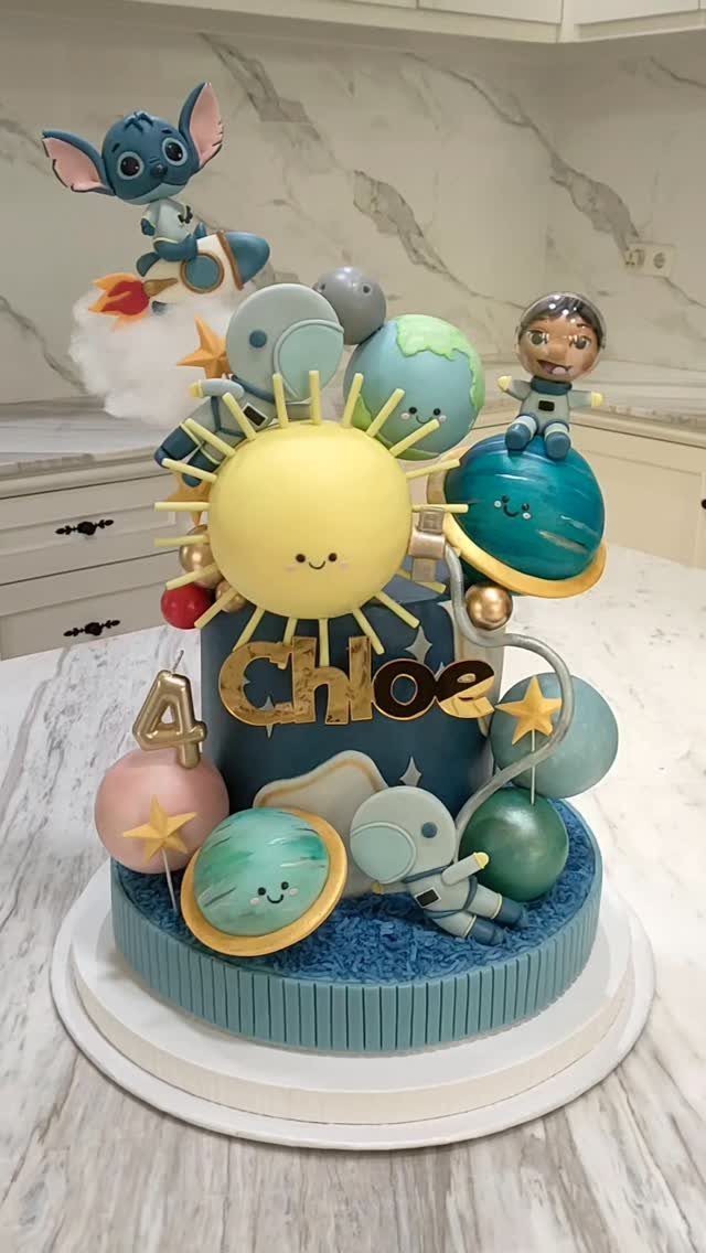 Space themed birthday cake with planets, astronauts, and a smiling sun for Chloe.