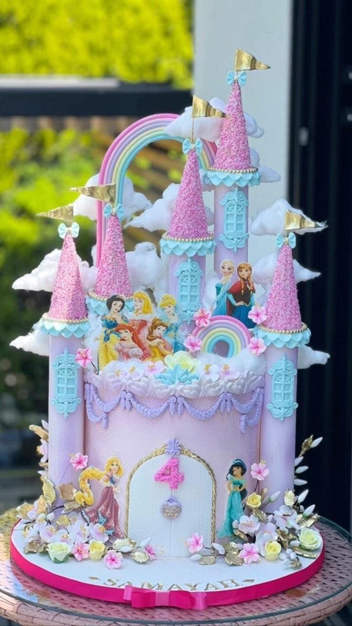 Princess castle cake with pink glittery spires, a rainbow, and Disney princess figures.