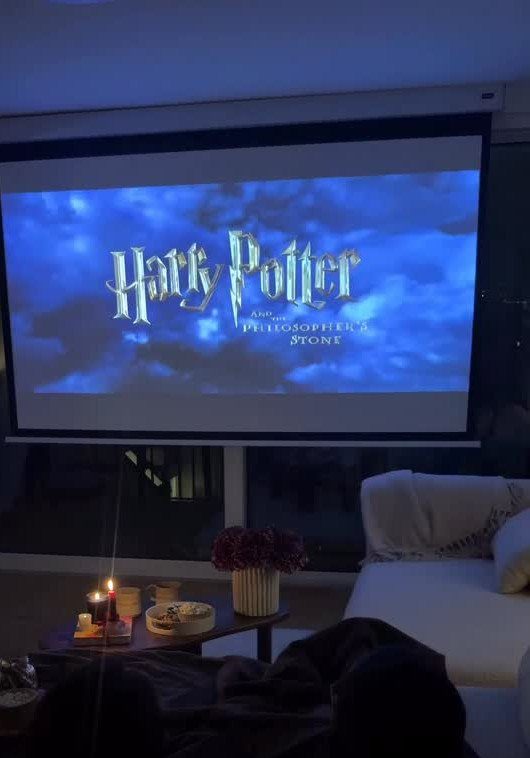 Projector screen showing Harry Potter movie with snacks and blankets in a cozy room