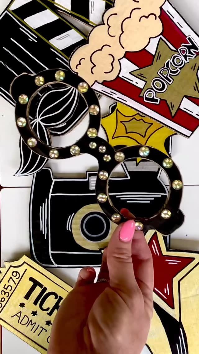 Movie-themed cardboard photo booth props including glasses, popcorn, and a clapperboard.