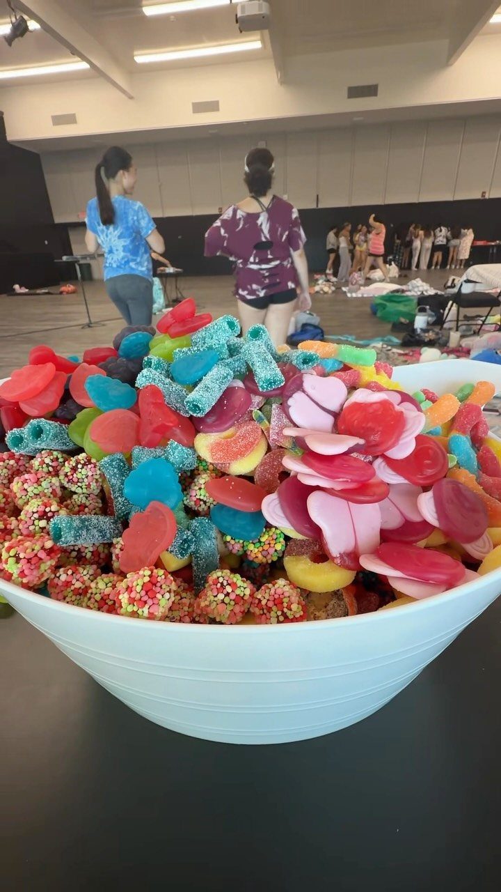 Large white bowl filled with colorful gummy candies and sweets in a room.