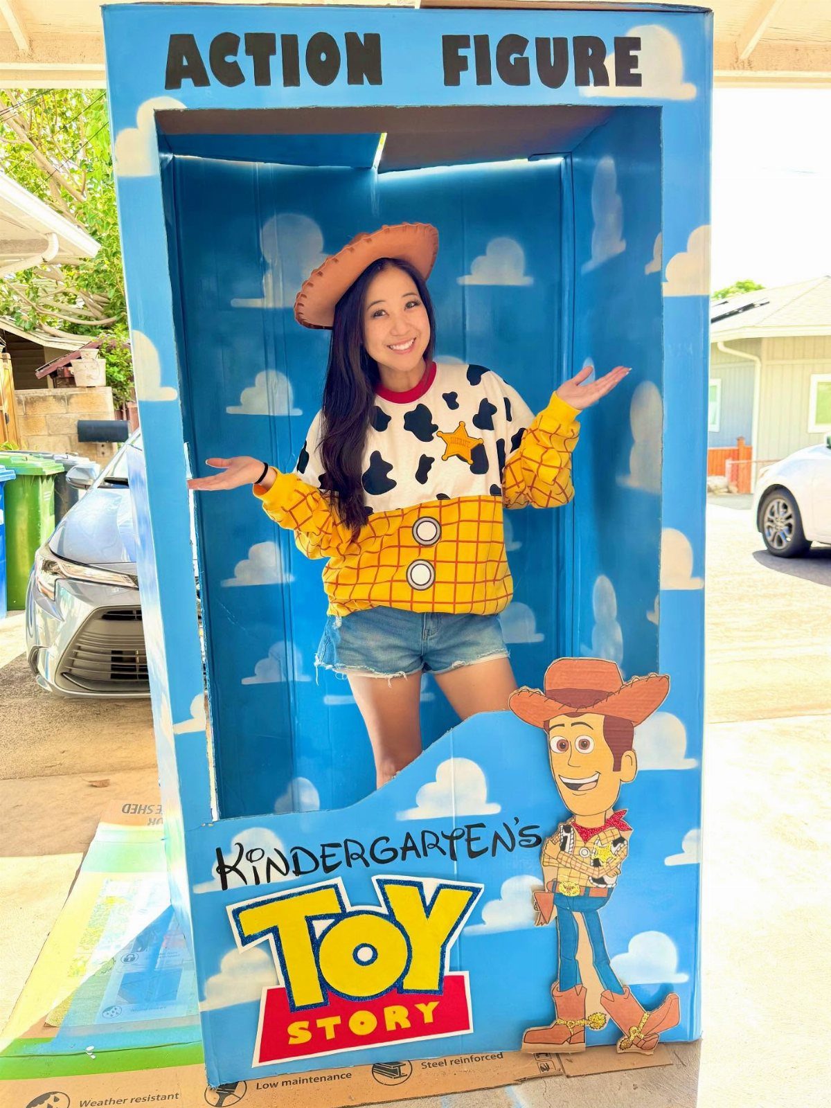 Woman posing inside a giant Toy Story action figure box photo prop outdoors.