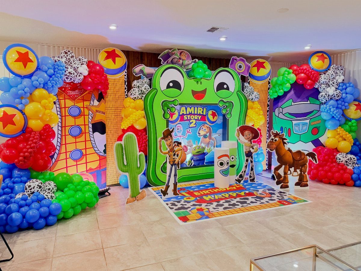 Toy Story party decorations with colorful balloon arches and character cardboard cutouts.