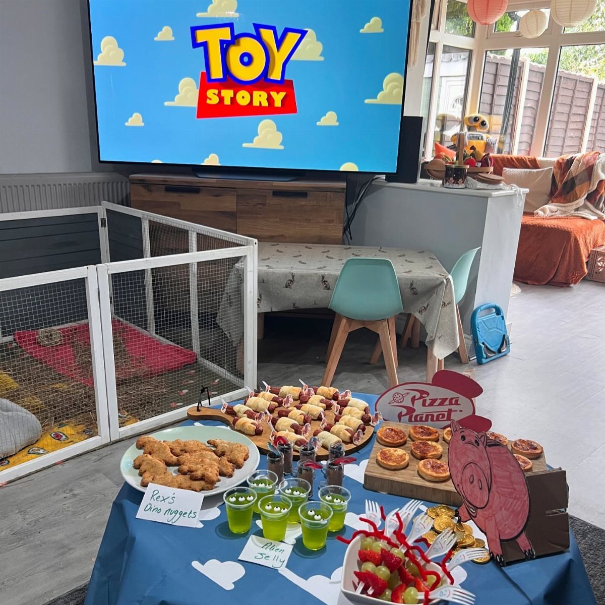 Toy Story themed party food spread with themed labels, snacks, and Pizza Planet signage.