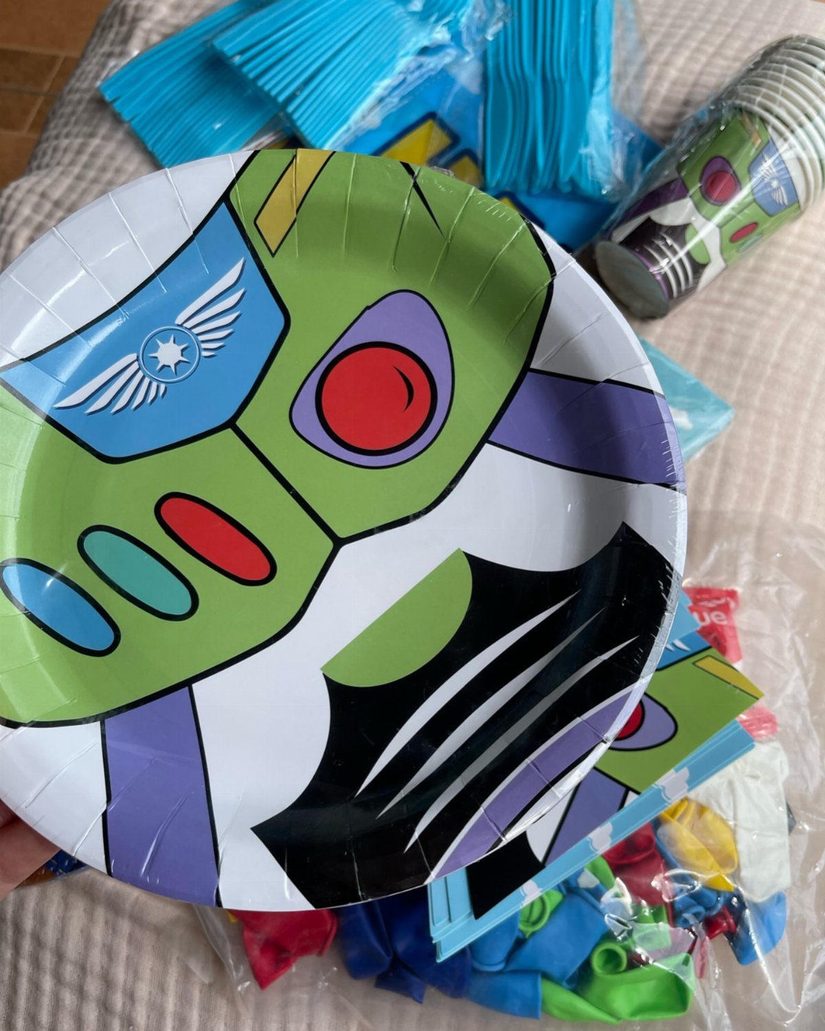 Buzz Lightyear themed paper plate held over party supplies and colorful balloons.
