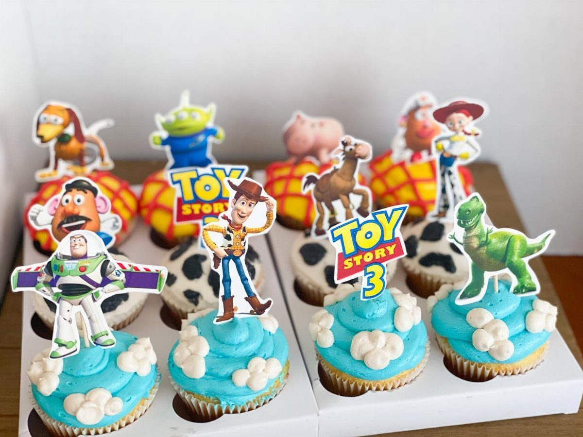 Toy Story cupcakes with blue frosting and character cardboard toppers in a box.