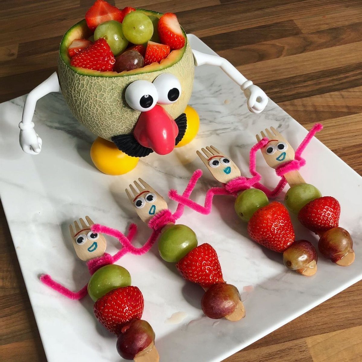 Melon carved as a Toy Story alien filled with fruit and fruit skewers.
