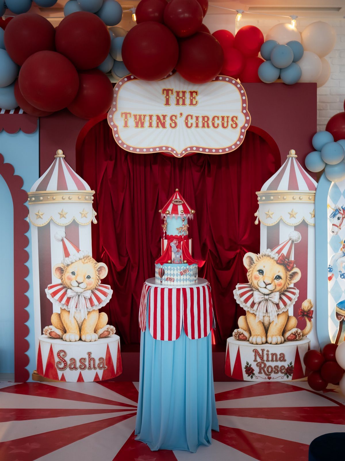 Circus party decorations with red curtains, lion cutouts, and a themed birthday cake.