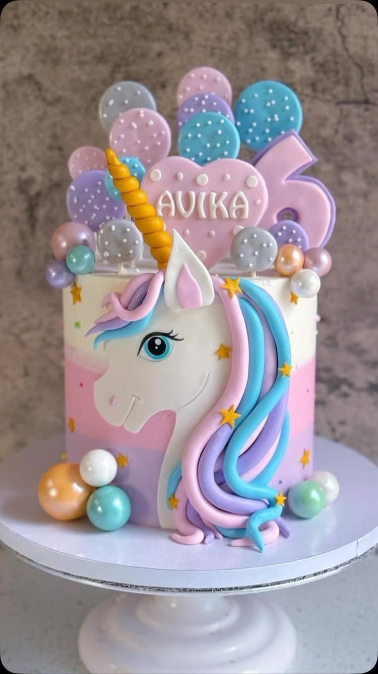 Unicorn cake with ombre frosting, golden horn, and pastel bubble decorations on top.