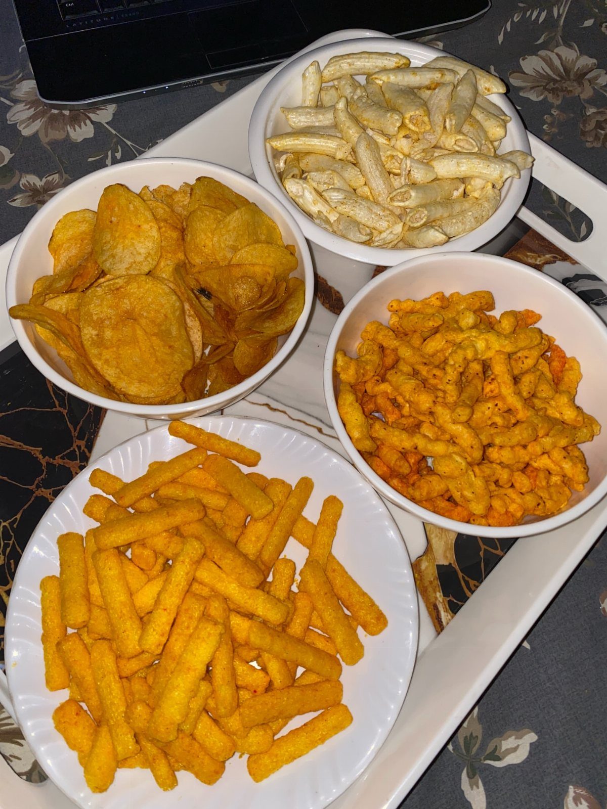 Four white bowls of assorted savory snacks on a white serving tray.